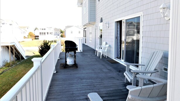 A covered wooden deck with outdoor seating and a barbecue grill. - Spacious 6BR Family Home – Just 3 Blocks to Bethany Beach in The Canal Community (Bethany Beach)