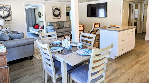 Una sala de estar moderna con comedor, un televisor de pantalla plana en la pared y una zona de cocina con mostrador.