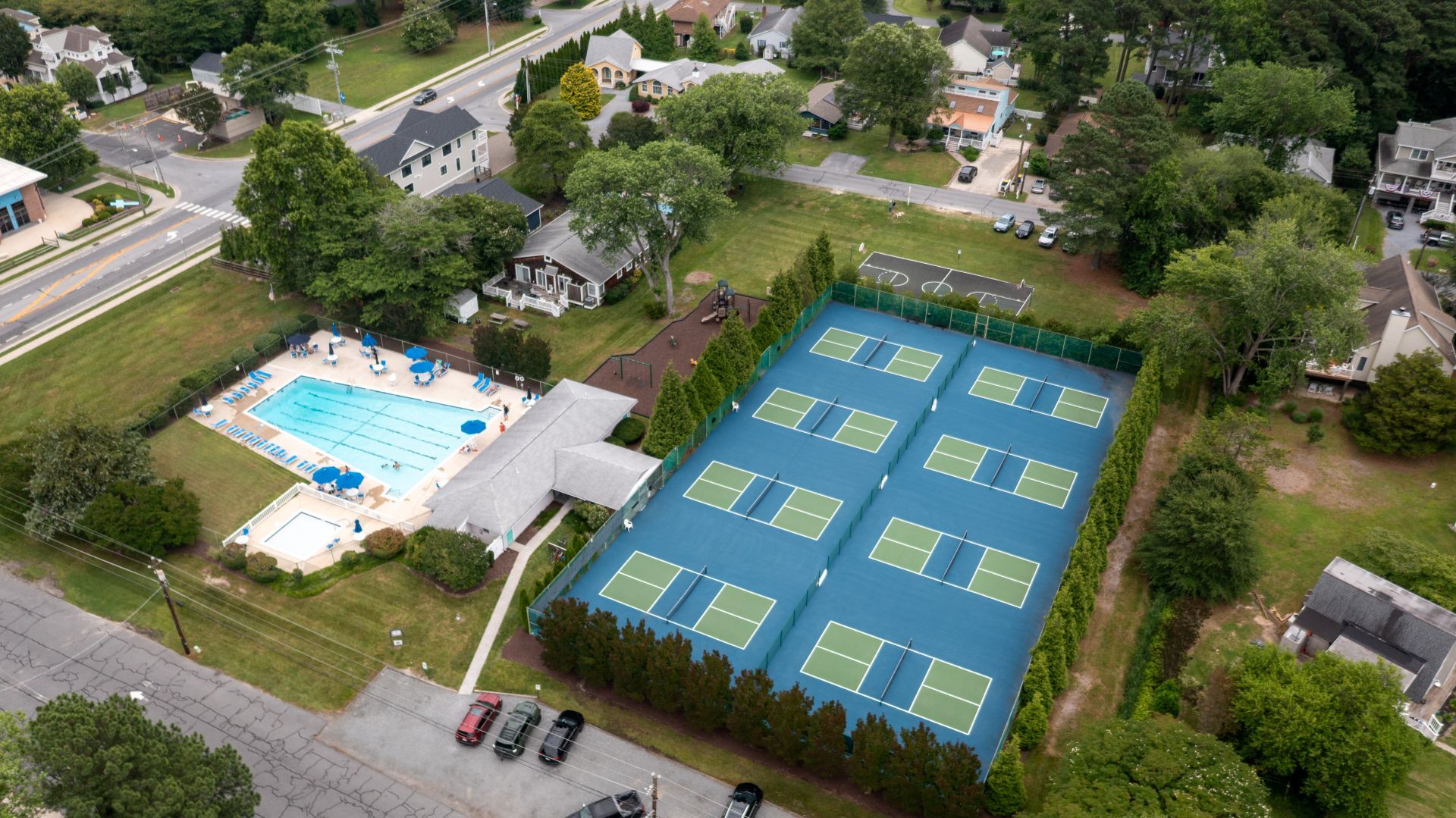 Vista aérea de una zona residencial con piscina y canchas de tenis.