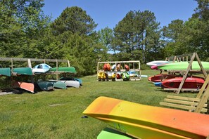 A grassy area with multiple kayaks and canoes stored on wooden racks. - 511 Doral Drive - Bethany West (Bethany Beach)