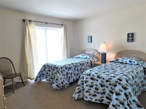 6 South Carolina Avenue - Twin Guest Room - Perfect for children or additional guests, this bright room features two twin beds with nautical blue and white bedding. Large sliding doors open to the exterior, keeping the room feeling fresh and connected to the outdoors.
