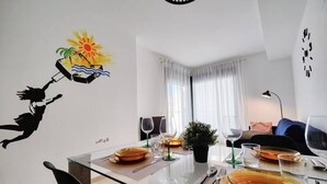 Comedor con mesa de vidrio dispuesta para dos, una planta en maceta y un adhesivo mural de una persona sumergiéndose en el agua.