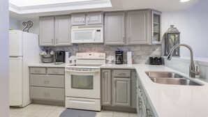 Une cuisine moderne avec des meubles blancs, un four à micro-ondes encastré, une cuisinière et un évier.