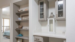 Une salle de bain aux murs blancs, avec un lavabo et des étagères remplies de produits de toilette.
