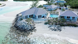 A coastal property with multiple blue-roofed buildings, a swimming pool, and a rocky shoreline. - Always Calm Beach. No Estate like this in Exuma! Brand New on protected sand bar (Little Exuma, Exuma)