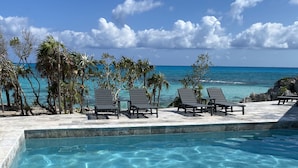 A clear pool with two stingrays swimming, surrounded by lounge chairs and palm trees, with a view of the ocean. - Always Calm Beach. No Estate like this in Exuma! Brand New on protected sand bar (Little Exuma, Exuma)