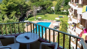 Un balcón con piscina, mobiliario de exterior y vistas a un paisaje exuberante.
