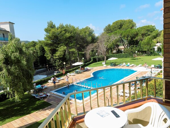 A pool area with a curved pool, lounge chairs, and umbrellas.
