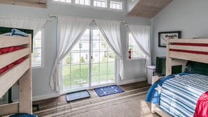 Una habitación con dos literas, una ventana con cortinas, un ventilador de techo y vistas al exterior.