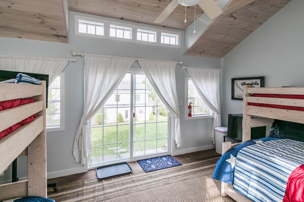 A room with a bunk bed, a window with curtains, a ceiling fan, and a framed picture on the wall. - Visit this Beautiful Lakehouse on Skaneateles Lake!! (Skaneateles)