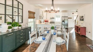 Una cocina amplia con comedor, que incluye una isla grande, electrodomésticos modernos y un candelabro.