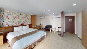 A hotel room with a large bed, a desk, a chair, a sofa, and a wardrobe.