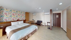 Hotellihuone, jossa on suuri sänky, työpöytä, tuoli, sohva ja vaatekaappi.