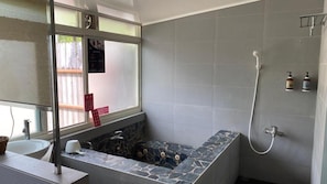 A bathroom with a stone bathtub, a sink, and a shower.