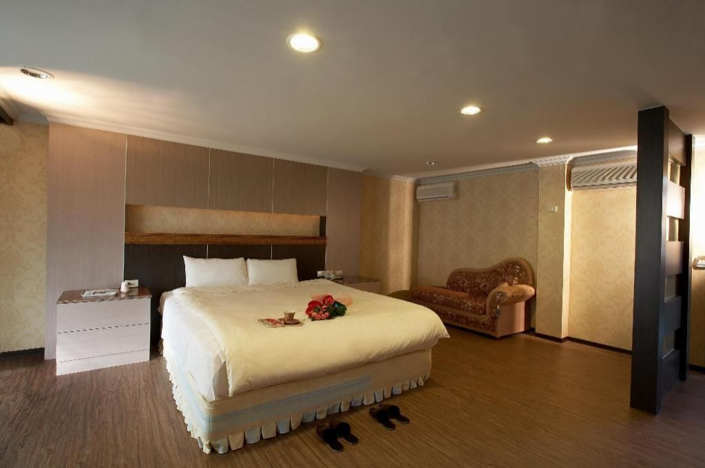 Une chambre d’hôtel avec un grand lit, un canapé, une table de chevet et une armoire.