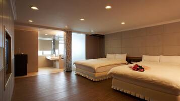A hotel room with two beds, a bathroom, and a large window.