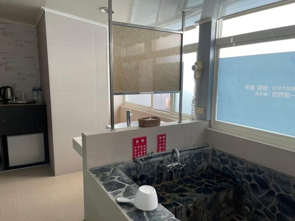 A bathroom with a stone sink, a mirror, a window, and a towel rack.