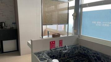 A bathroom with a stone sink, a mirror, a window, and a towel rack.