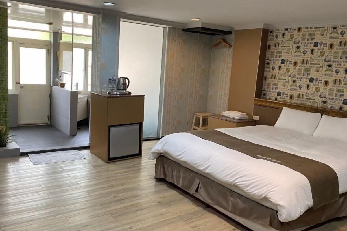 Une chambre d’hôtel avec un lit, un bureau doté d’une bouilloire, une petite table et un mur orné d’un motif.
