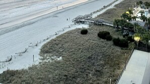 A beach with a boardwalk and a pier extending into the water.