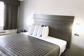 A hotel room with a large bed, a dark headboard, and a geometric-patterned bedspread. - Americas Best Value Inn & Suites San Antonio Arena District (San Antonio)