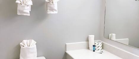 Une salle de bain équipée d’un WC, d’un lavabo, d’un miroir et d’un porte-serviettes avec des serviettes.