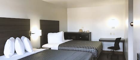 A hotel room with two beds, a desk, a chair, and a nightstand.