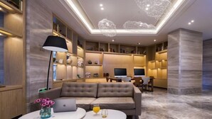 Un salon moderne avec un canapé, deux petites tables rondes blanches, un ordinateur portable et une lampe.