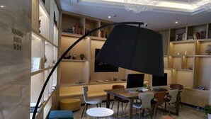 Un salon moderne avec une lampe noire aux lignes courbes, un coin repas comprenant une table et des chaises, et une bibliothèque remplie de livres.