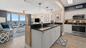 Cocina moderna con una isla grande, muebles blancos, electrodomésticos de acero inoxidable y vistas al exterior.