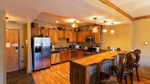 Una cocina moderna con armarios de madera, electrodomésticos de acero inoxidable y una isla central con taburetes de bar.