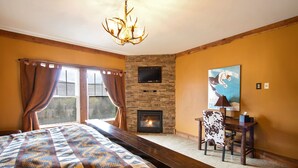 Una habitación con cama, chimenea, televisor y un cuadro.