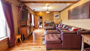 Una sala de estar acogedora con piso de madera, sofás de cuero, un televisor y una chimenea.