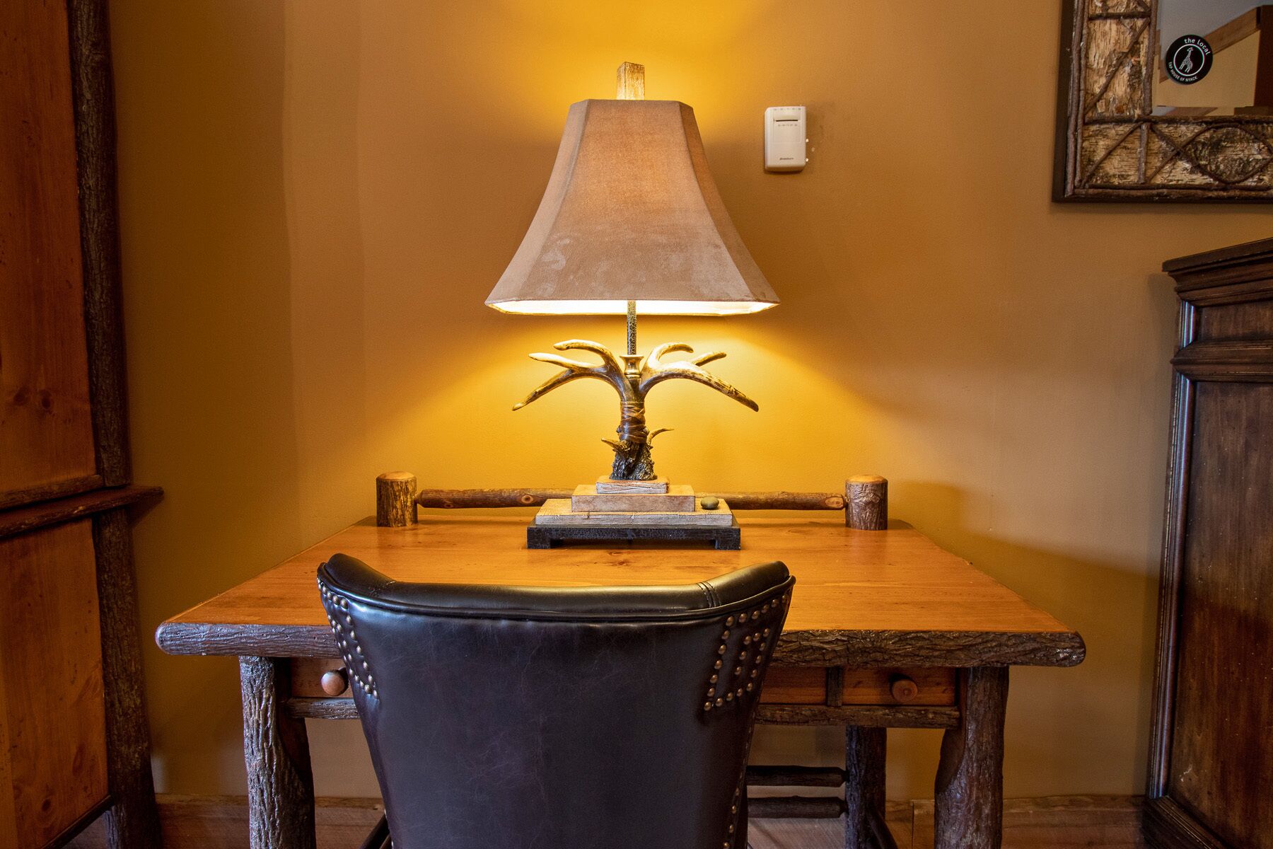 A dining table with a lamp, chairs, and a wooden cabinet.