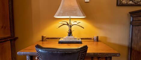 A dining table with a lamp, chairs, and a wooden cabinet.