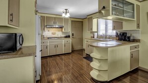 A kitchen with a central island, white cabinets, a microwave, and a coffee maker. - Quiet suburban home 10 minutes from airport/25 min from Niagara Falls (Depew)