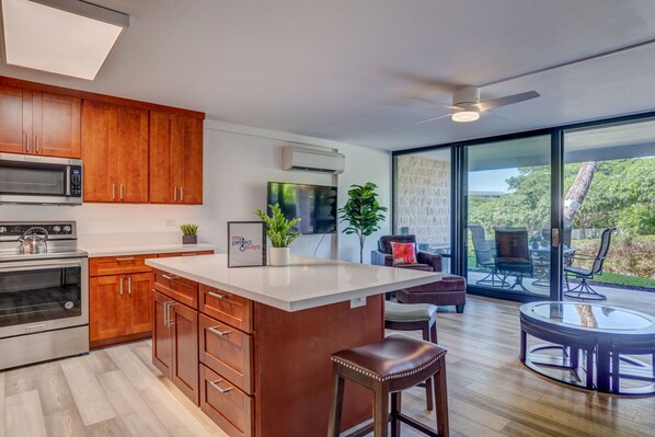 A modern kitchen with wooden cabinets, stainless steel appliances, a large island, and a dining area with a glass table and chairs.