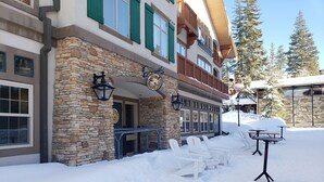 A stone building with a balcony and outdoor seating area covered in snow. - Ski-in / Ski-out best Solitude Resort Village Location (Cottonwood Heights)