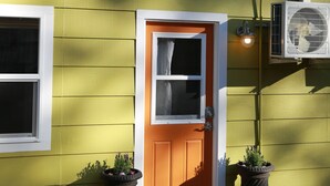 A house with a yellow exterior, a brown door, and two potted plants at the entrance. - Everything Evergreen (Prescott)