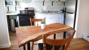 A kitchen with a wooden table, chairs, a potted plant, and modern appliances. - Everything Evergreen (Prescott)