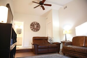 Relax in this inviting living room with a comfortable sofa, ceiling fan, and lamp.