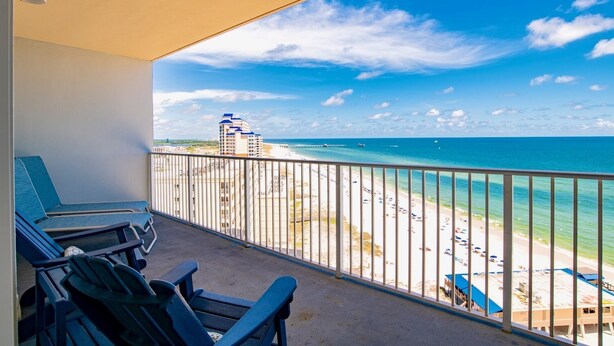 A balcony with a view of a beach and a pier.