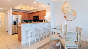 A modern kitchen with wooden cabinets, stainless steel appliances, and a glass island with bar stools.