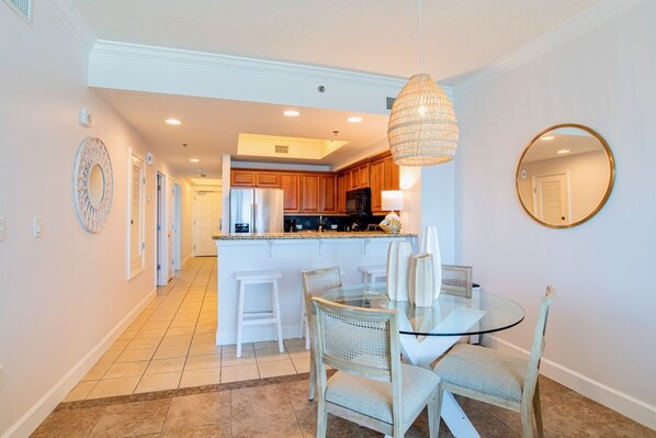 A modern kitchen with wooden cabinets, a central island, and a dining area with glass tables and wicker chairs.