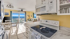 A kitchen with a stove, microwave, and a dining area with chairs and a table.