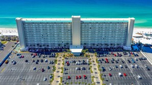 A large hotel with a central atrium, multiple floors, and a parking lot in front.