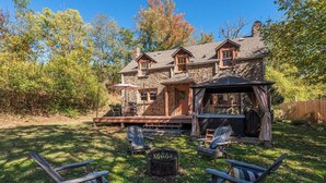 A stone house with a deck, outdoor seating, and a fire pit.