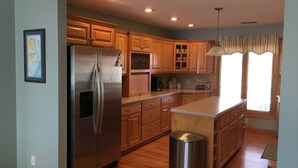 A modern kitchen with wooden cabinets, a stainless steel refrigerator, and a built-in island.