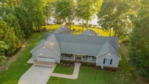 A two-story house with a garage, a covered porch, and a well-maintained lawn.