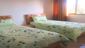 Een kamer met twee bedden, elk met een houten hoofdbord en een bloemenprint sprei.
